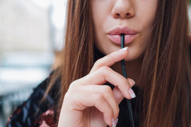 Woman with sexy lips drinking through a straw