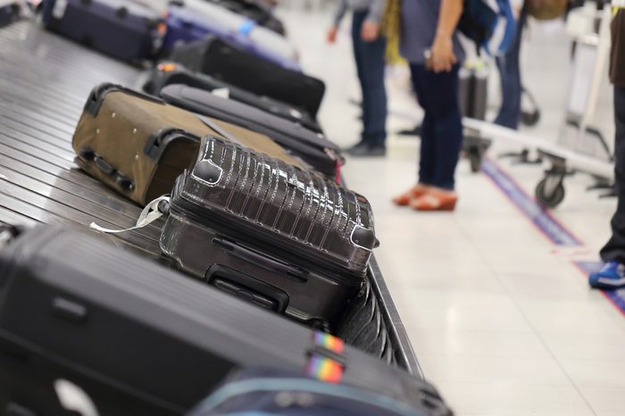 image of people picking up suitcase on luggage conveyor belt in the airport
