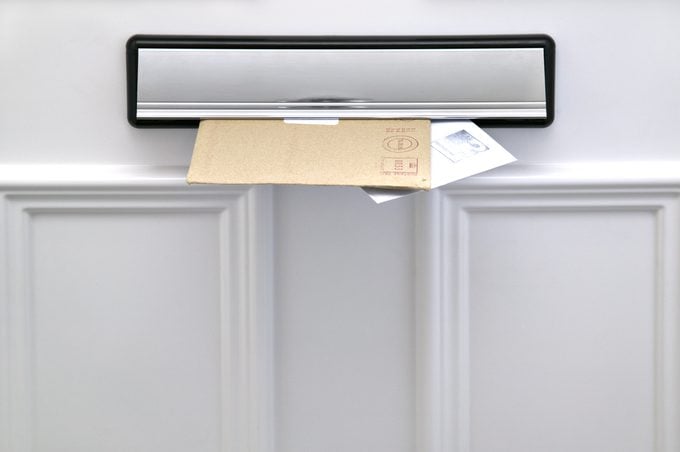 Two letters sticking out of a letterbox on a white door, space for copy