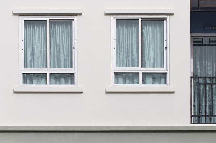 Two modern windows with uv protection curtain on white wall, outdoor view