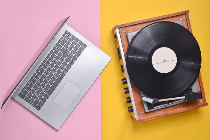 Laptop, vinyl player on a colored pastel background. Modern and outdated technology, top view