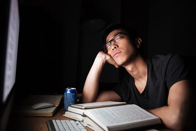 Tired exhausted asian young man studying and sleeping in front of computer in nighttime