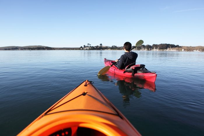 A man and red kayak in a lake with open view.