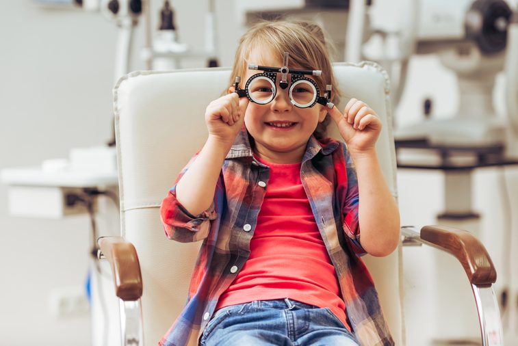 Little boy looking at camera and smiling while sitting on chair at the ophthalmologist