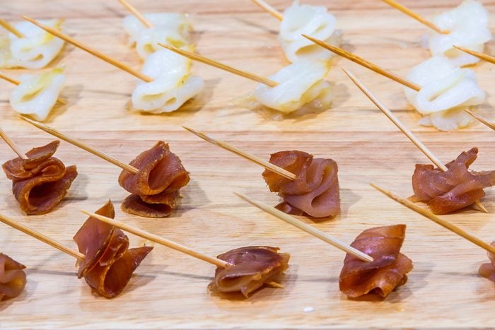 Advertising, Business, Food, Health Concept - Offering food samples to customers in shop. Smoked tuna on a wooden stick. Select focus