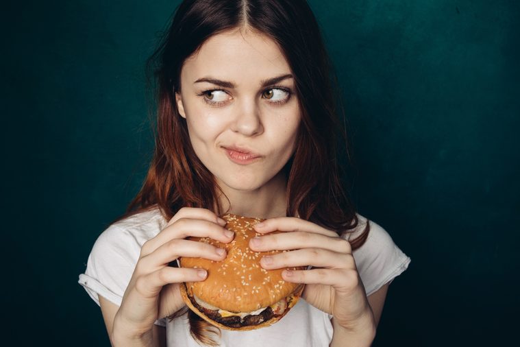 Woman with burger in hand, hungry woman eating a burger and did not want to share a Food