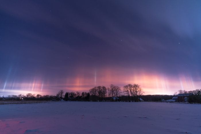 Beautiful light pillars during a freezing winter night, with lot's of snow, trees and beautiful sky.