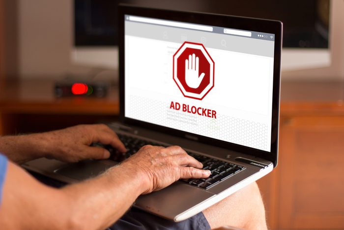 Cropped image of a senior man using laptop and ad blocker on the screen