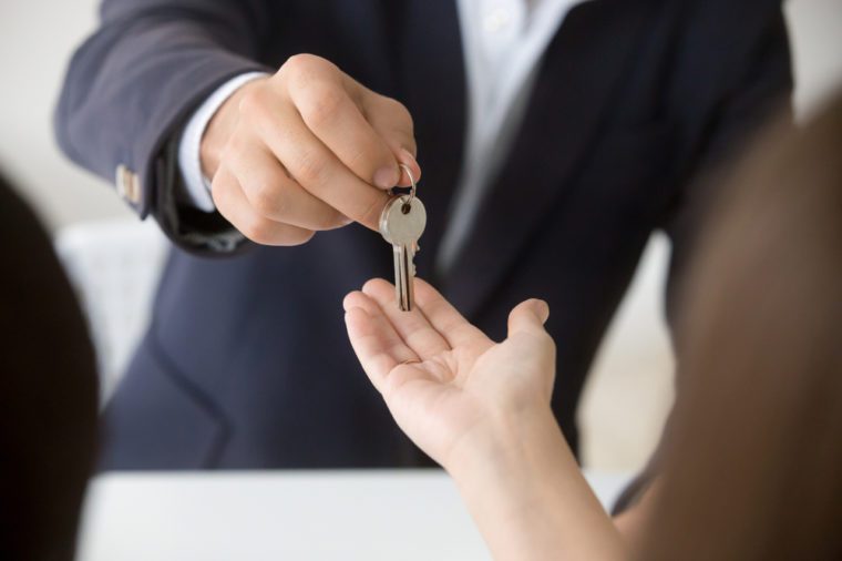 Realtor giving woman keys to new apartment, agent making deal with client buyer owner tenant renter buying or renting real estate, mortgage loan investment and property purchase, hands close up view