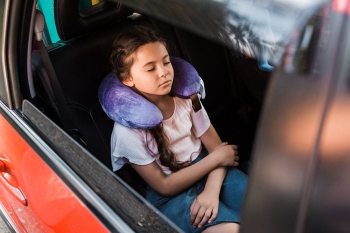 adorable kid sleeping in car with neck pillow