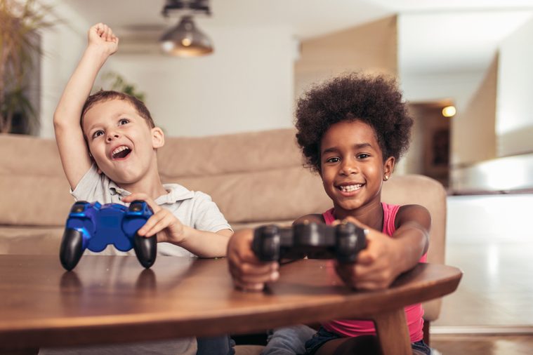 Boy and girl sitting in living room playing video game together