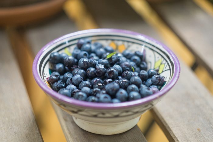 Ripe forest blueberries (bilberry, whortleberry, blaeberry, huckleberry) in a patterned bowl on a sunny summer day. Fresh organic berries