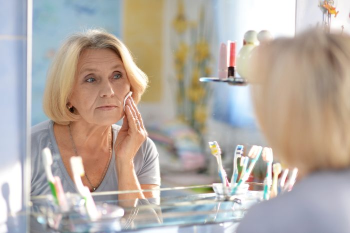 beautiful elderly woman doing make-up in the bathroom