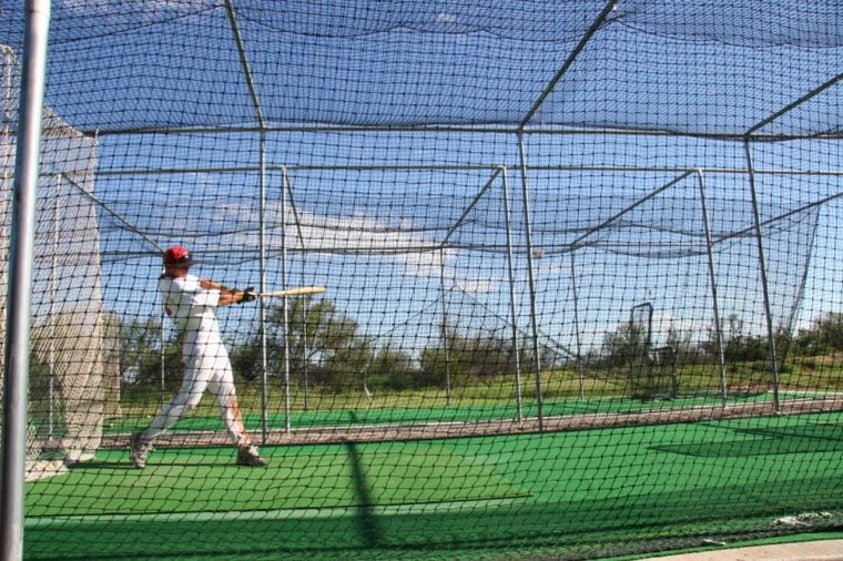 practicing hitting baseball in a batting cage