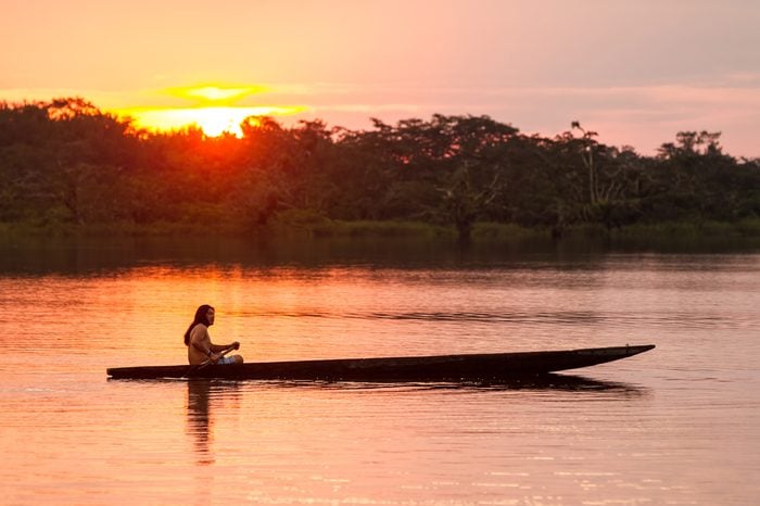 INDIGENOUS ADULT MAN WITH CANOE ON LAGOON GRANDE, CUYABENO NATIONAL PARK, ECUADOR AT SUNSET, MODEL RELEASED