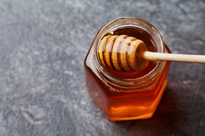 Honey in a pot or jar on kitchen table, top view