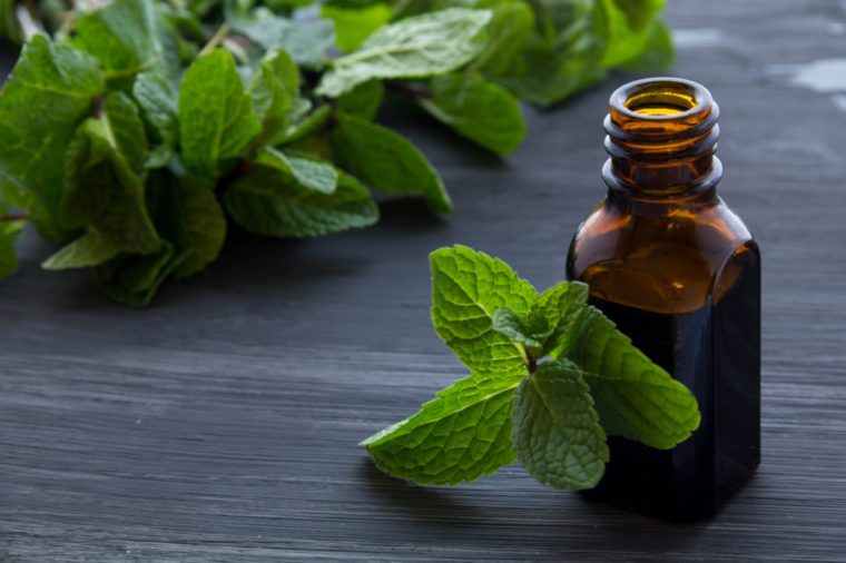 Essential aroma oil with peppermint on wooden background.