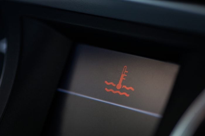 Close up shot of a car's electronic dashboard, with coolant warning on.