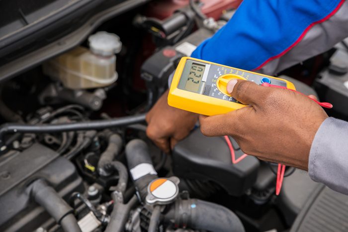 Close-up Of Mechanic Checking A Car Battery Level With Multimeter