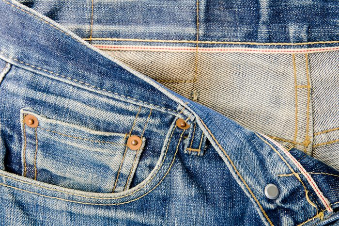 Details of jeans male. The front waist of the pants with red seam.