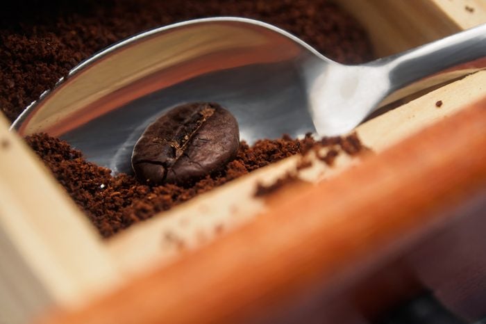 Spoon with coffee bean and grounded coffee. Grounded coffee.