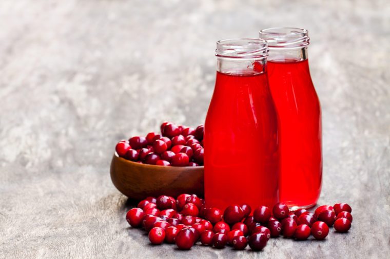 Organic cranberry juice in bottles with berries on wooden background