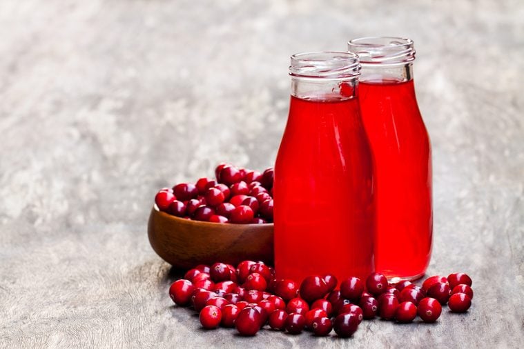 Organic cranberry juice in bottles with berries on wooden background