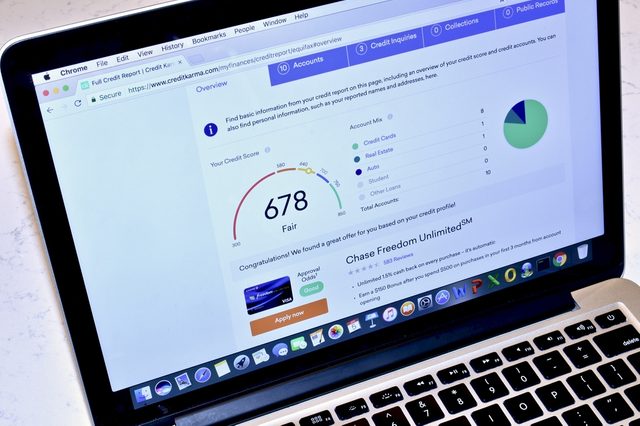 An Apple MacBook Pro displaying the Credit Karma webpage with relevant credit score information.