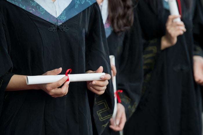 people in a gown holding a diploma.
