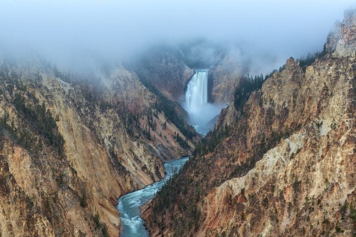Morning fog lifts above the Lower Falls of the Yellowstone River in Wyoming, USA