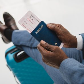 Cropped image of African american man holding passport and fly ticket in hands
