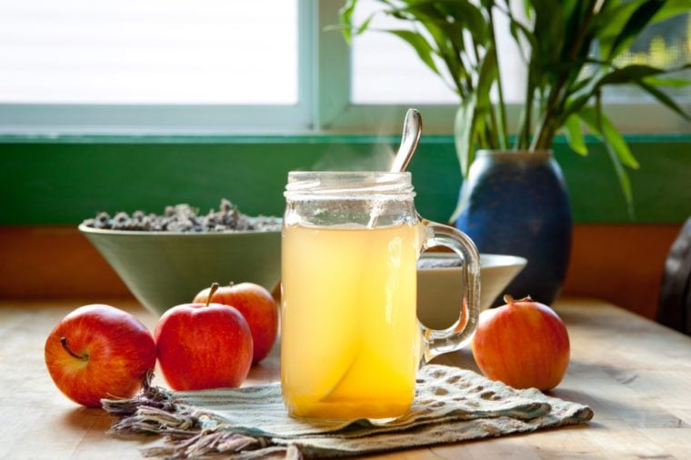 Hot apple cider vinegar and honey drink with apples on a table