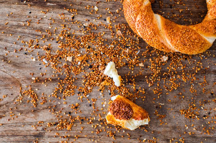 Turkish bagel simit pieces and sesame seeds crumb on wooden background