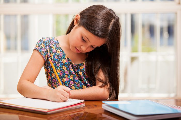 Beautiful little girl looking focused and concentrated on doing her homework