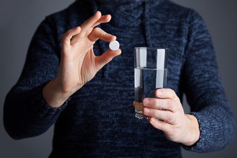 Male ready to dissolve the pill in water. Soluble white pill and a glass of water in his hands. Effervescent tablet aspirin in glass of water