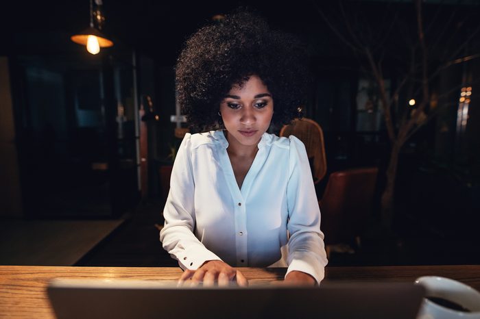 Young black businesswoman working late on laptop in office. Beautiful female entrepreneur using laptop while sitting at a table.