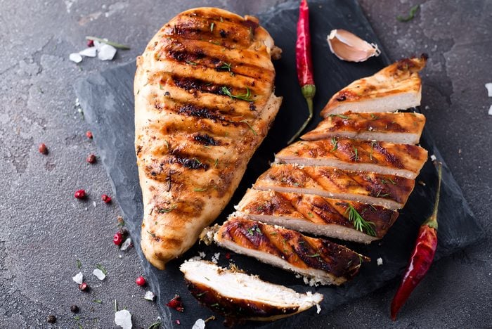 Marinated grilled healthy chicken breasts on a stone board,