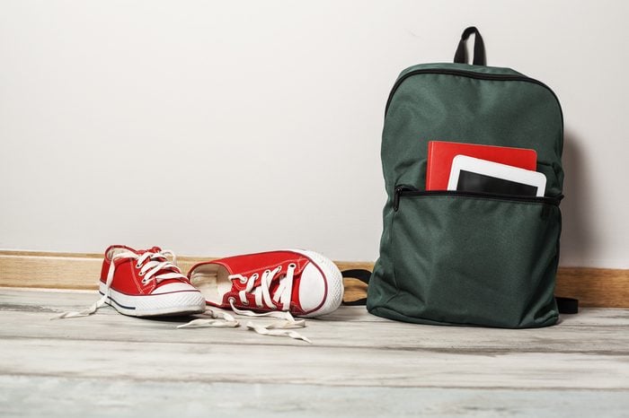 Red sneakers with school bag on wooden background