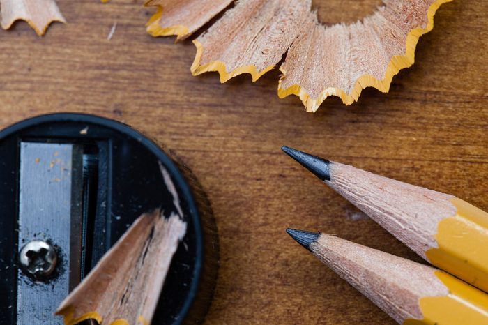 A macro image of two sharpened pencils, a sharpener, and their shavings