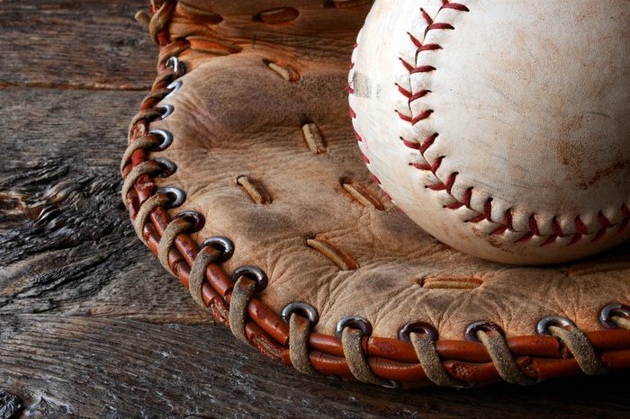 A low angle image of an old used baseball and leather baseball glove.