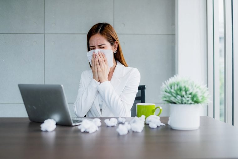 office syndrome allergy with business woman sick and sneeze with tissue and fever