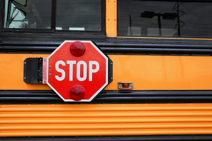 parlak sarı turuncu bir okul otobüsünün geniş açılı ön görünümü ve büyük kırmızı dur işareti