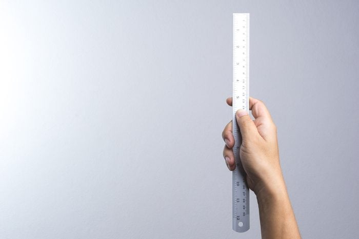Hand holding a ruler on white background