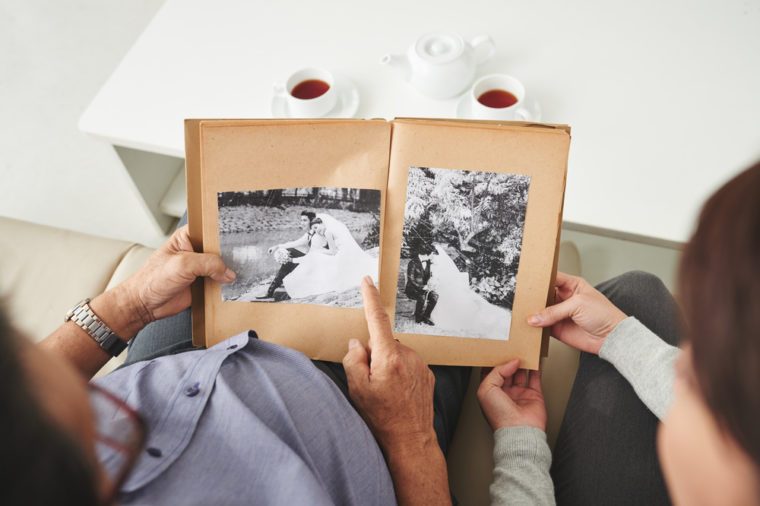 Senior man showing old wedding photos to his granddaughter