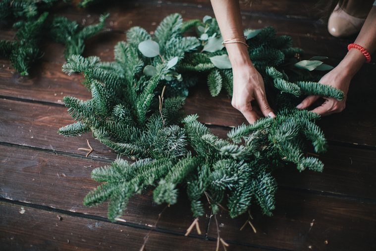 Woman making christmas wreath on a dark wooden table. Concept of florist's work before christmas holidays.