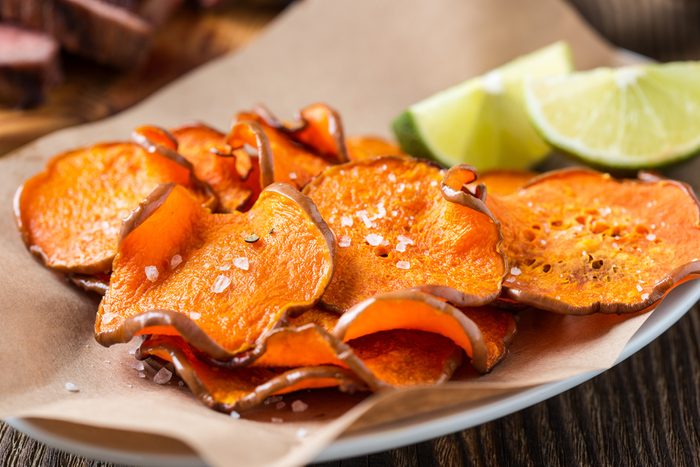 Homemade organic baked pumpkin chips served with lime wedges on kraft paper