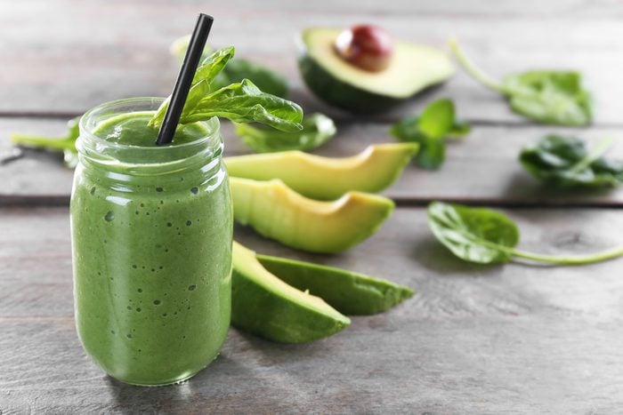 Fresh avocado smoothie with slices on wooden background