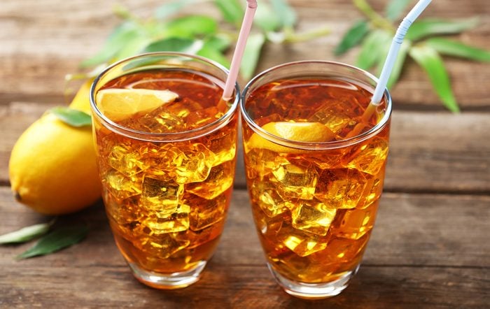 Two glasses of iced tea with lemon on wooden background
