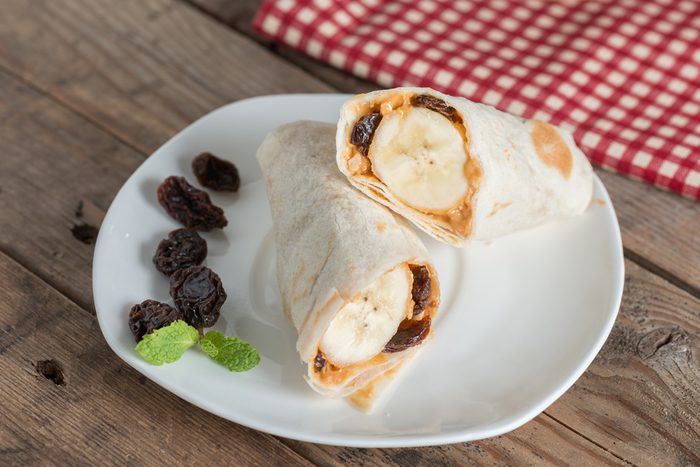 Slice tortilla wrap with peanut butter, raisin and banana.