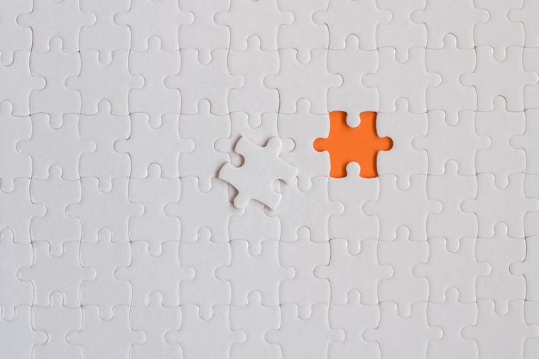 White details of jigsaw puzzle on orange background.
